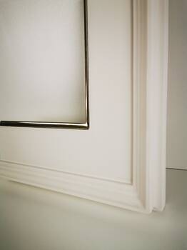 Zbliżenie faktury białej ramy lustra z krawędzią pozłoconą złotem księżycowym 22 karat.