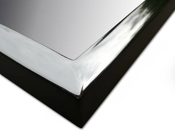 Zbliżenie narożnika lustra w srebrnej ramie z połyskiem i czarnymi bokami