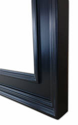 Zbliżenie narożnika dużego lustra w czarnej ramie z litego drewna